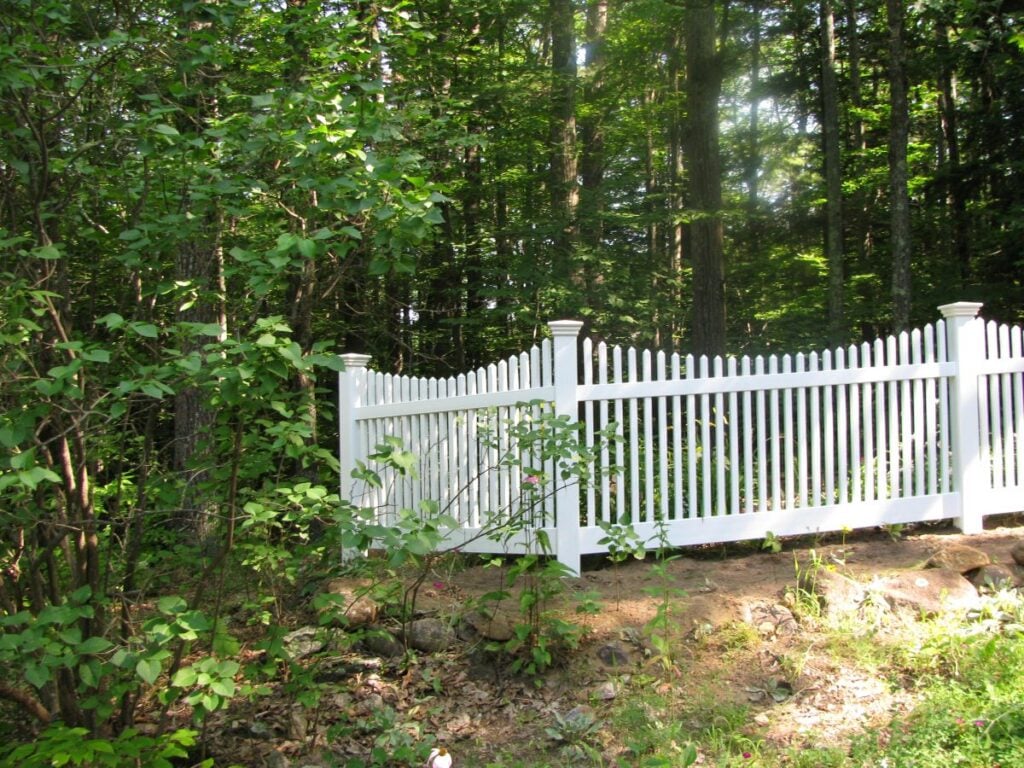 white picket fence surrounded by greenery