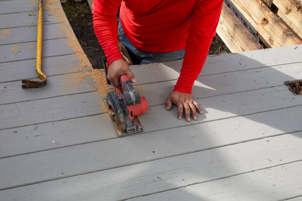 deck repair cost worker cutting grey wooden planks on a deck