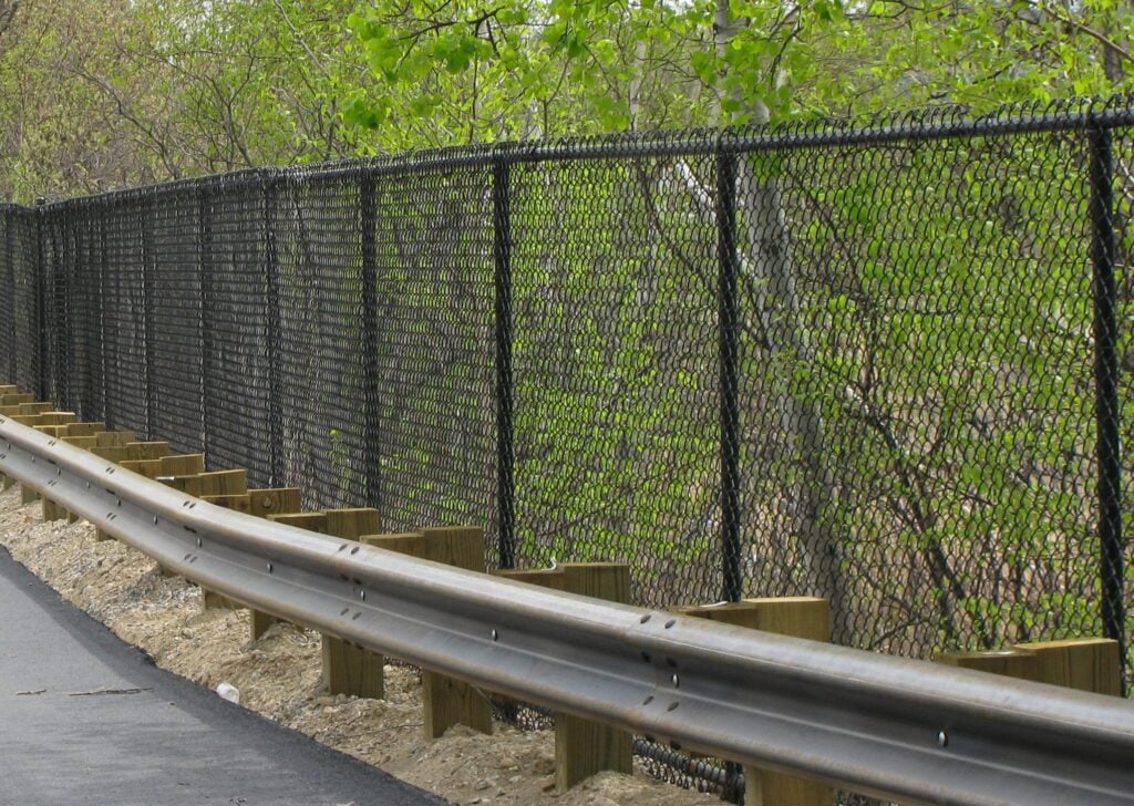 a black chainlink fence next to a road