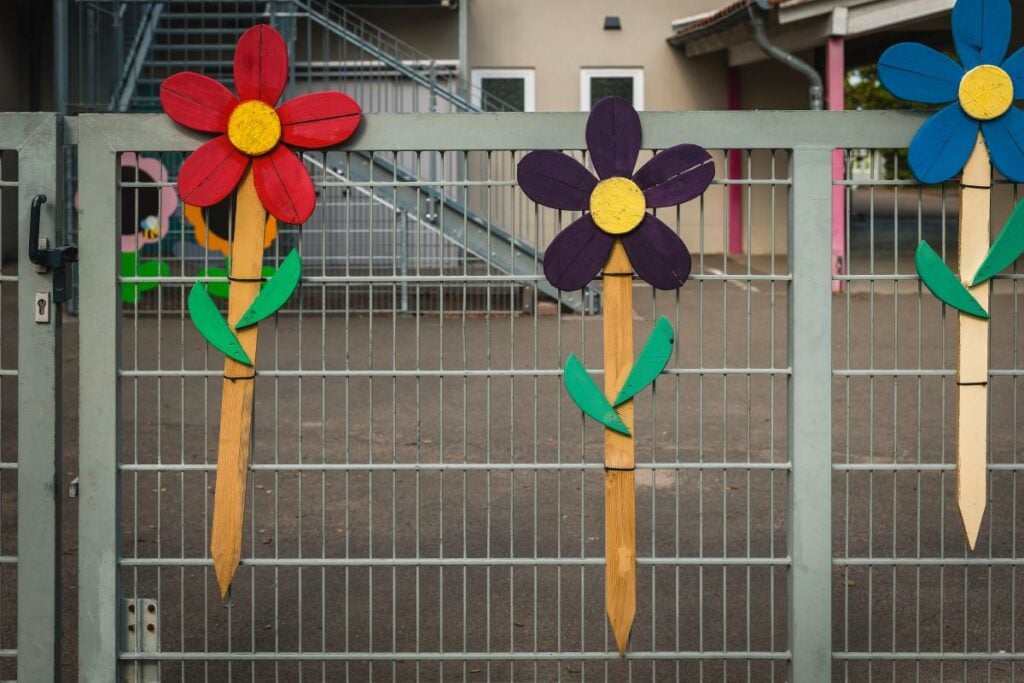 Colorful wooden flowers brighten up a school fence