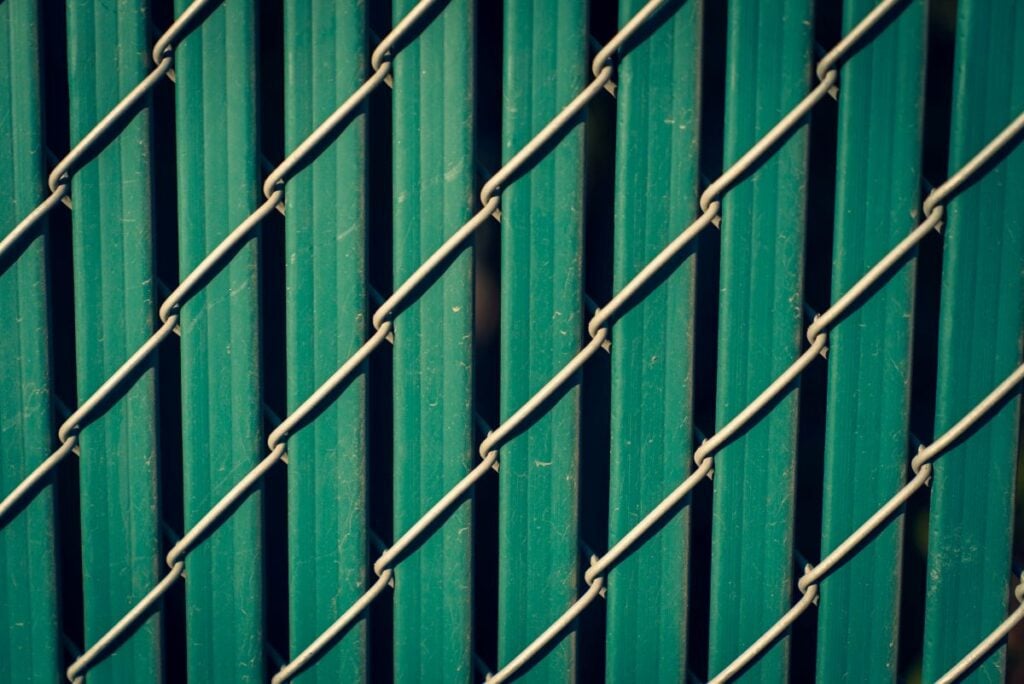 Diagonal chain link fence with privacy fence slats in emerald green.