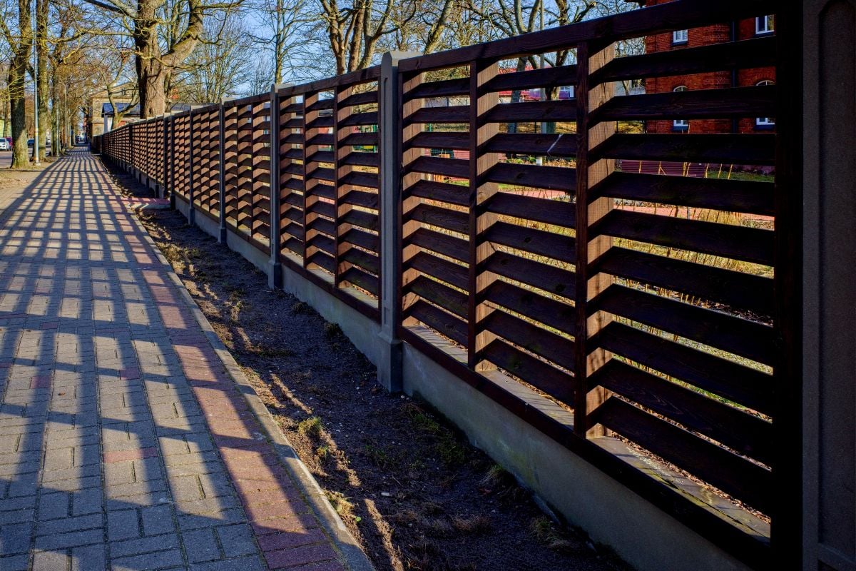 Long wooden fence. Fencing of private territory. Fence along the sidewalk.
