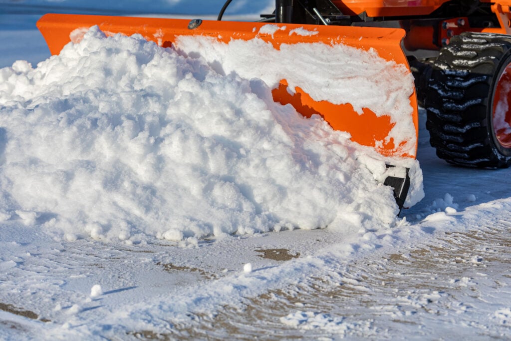 Snow removal from driveway with snowplow. Winter weather safety
