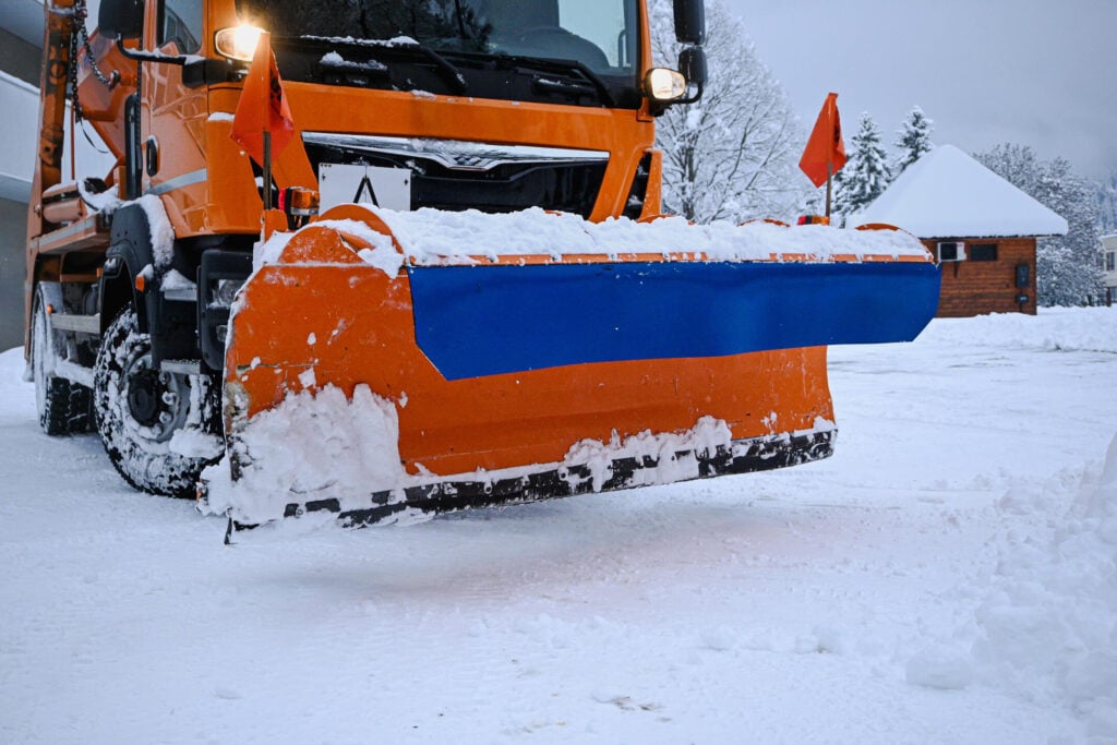 Snowplow truck with blade moving snow, providing road maintenance in winter