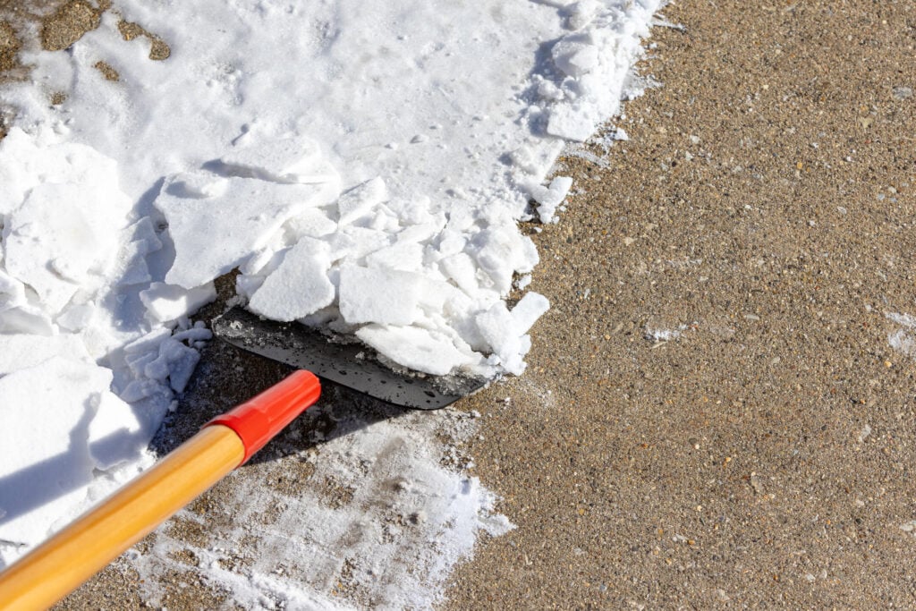 Using snow scraper or ice chopper to remove packed snow from sidewalk