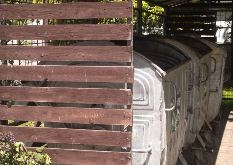 Waste container shelter with wooden partition and metal dumpsters