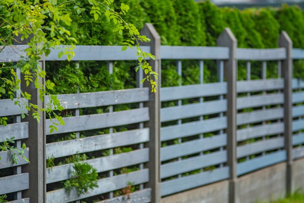 Gray wooden fence with concrete posts. Residential Perimeter Fence